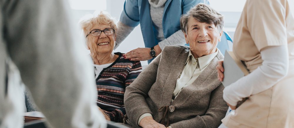 Smiling residents chatting with staff in an aged care home