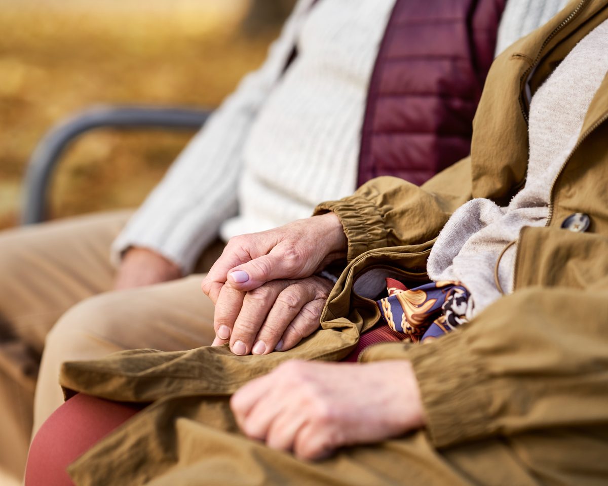 Close-up of an older person's hands resting together, held reassuringly